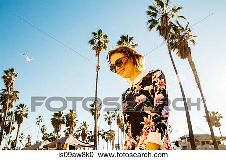 Young woman walking outside, near palm trees, low angle view View Large Photo Image Stock Image - Young woman walking outside, near palm trees, low angle view. Fotosearch