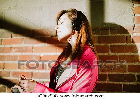 Young woman wearing headphones eyes closed smiling View Large Photo Image Stock Photo - Young woman wearing headphones eyes closed smiling. Fotosearch