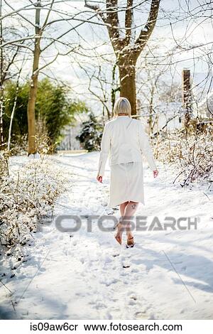 Young woman wearing white, walking in winter landscape, rear view View Large Photo Image Stock Photography - Young woman wearing white, walking in winter landscape, rear view. Fotosearch