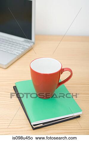 Mug on notebooks and laptop View Large Photo Image Picture - Mug on notebooks and laptop. Fotosearch