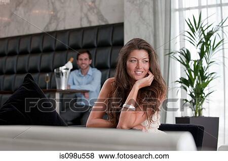 Young woman at table with man in background View Large Photo Image Stock Photo - Young woman at table with man in background. Fotosearch