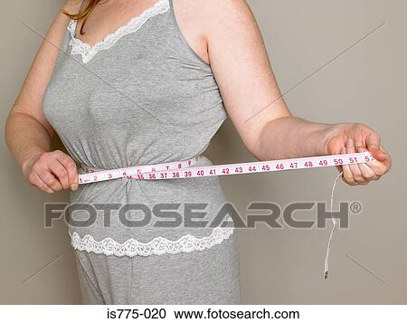 Woman measuring her waist View Large Photo Image Stock Image - Woman measuring her waist. Fotosearch