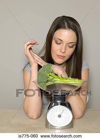 Young woman weighing broccoli View Large Photo Image Stock Image - Young woman weighing broccoli. Fotosearch