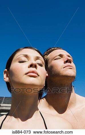 Stock Image - Couple in sunlight with eyes closed. Fotosearch