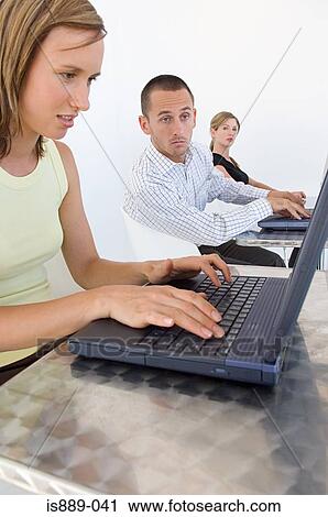 Stock Image - Man looking at woman s laptop. Fotosearch