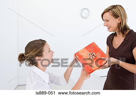 Woman giving colleague a gift View Large Photo Image Stock Image - Woman giving colleague a gift. Fotosearch