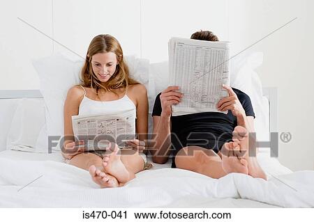 Stock Image - Couple reading newspapers in bed. Fotosearch