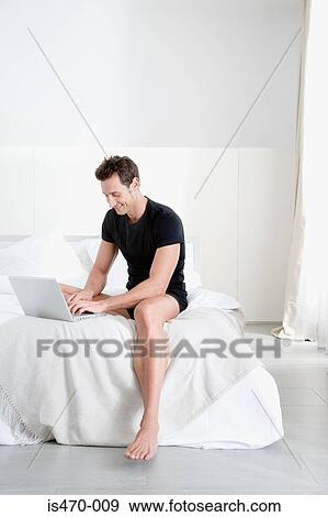 Man using laptop on bed View Large Photo Image Stock Photo - Man using laptop on bed. Fotosearch