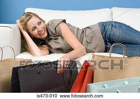 Stock Image - Woman reclining on sofa. Fotosearch