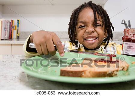 Boy spreading jam on toast View Large Photo Image Stock Image - Boy spreading jam on toast. Fotosearch