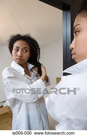 Stock Image - Young woman styling hair. Fotosearch