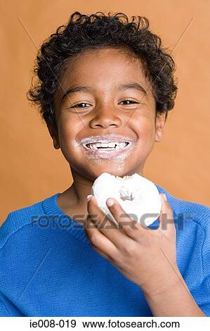 Boy eating a doughnut View Large Photo Image Stock Photo - Boy eating a doughnut. Fotosearch