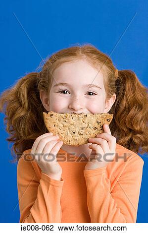 Girl holding a cookie over her mouth View Large Photo Image Stock Image - Girl holding a cookie over her mouth. Fotosearch