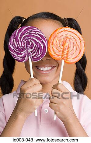 Girl holding lollipops over her eyes View Large Photo Image Stock Photo - Girl holding lollipops over her eyes. Fotosearch