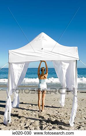 Stock Image - Woman practising yoga on a beach. Fotosearch