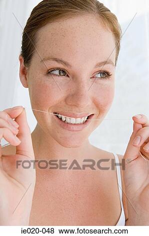 Stock Photo - Young woman flossing her teeth. Fotosearch