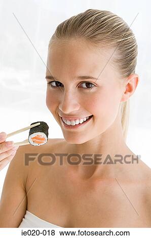 Young woman holding sushi with chopsticks View Large Photo Image Stock Photo - Young woman holding sushi with chopsticks. Fotosearch