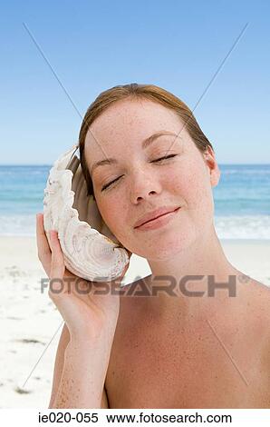 Young woman listening to shell View Large Photo Image Stock Photography - Young woman listening to shell. Fotosearch