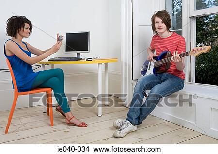 Girl photographing boy playing guitar View Large Photo Image Picture - Girl photographing boy playing guitar. Fotosearch