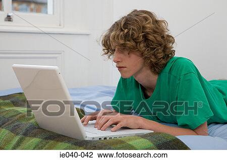 Stock Image - Teenage boy using laptop. Fotosearch