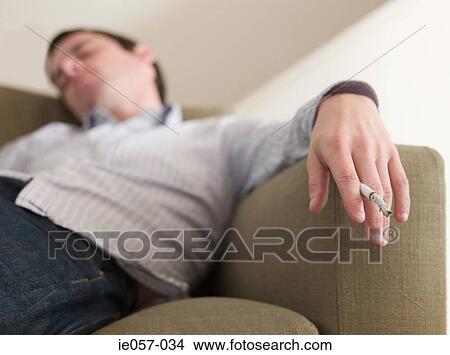 A man asleep with a cigarette in his hand View Large Photo Image Picture - A man asleep with a cigarette in his hand. Fotosearch