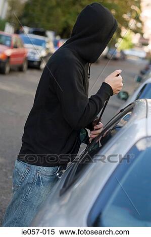 Stock Photography - A thief breaking into a car. Fotosearch
