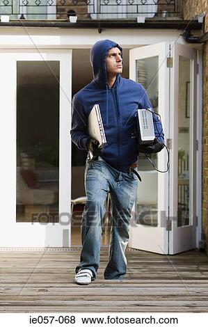 A thief carrying a laptop and a dvd player View Large Photo Image Stock Photo - A thief carrying a laptop and a dvd player. Fotosearch
