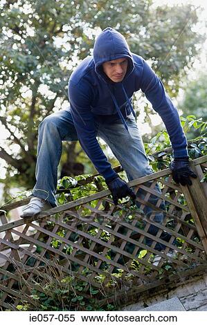 A thief climbing over a fence Stock Photography | ie057-055 | Fotosearch