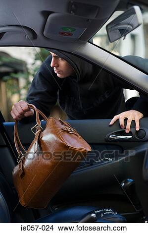 A thief stealing a bag out of a car View Large Photo Image Picture - A thief stealing a bag out of a car. Fotosearch