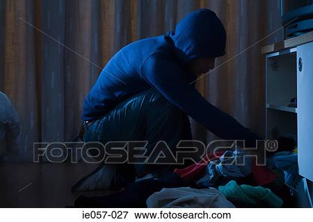 Stock Photo - Burglar looking through cupboard. Fotosearch