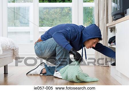 Stock Photography - Burglar looking through cupboard. Fotosearch