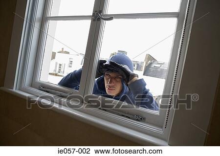 Stock Image - Burglar looking through window. Fotosearch