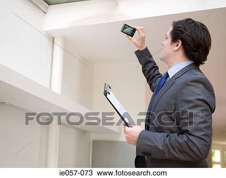 Stock Image - Surveyor photographing house. Fotosearch