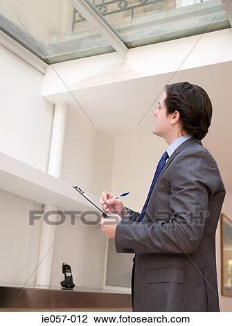 Stock Image - Surveyor writing on clipboard. Fotosearch