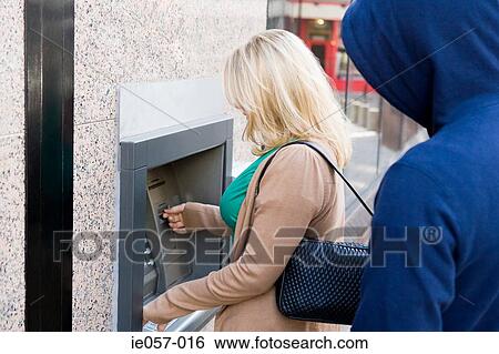 Thief looking over womans shoulder at cash machine View Large Photo Image Stock Photograph - Thief looking over womans shoulder at cash machine. Fotosearch