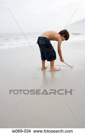 Boy drawing in the sand View Large Photo Image Picture - Boy drawing in the sand. Fotosearch