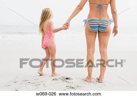 Stock Photograph - Girl and mother holding hands on beach. Fotosearch