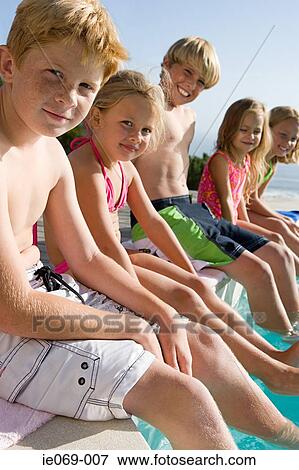 Stock Photo - Kids sitting on edge of swimming pool. Fotosearch