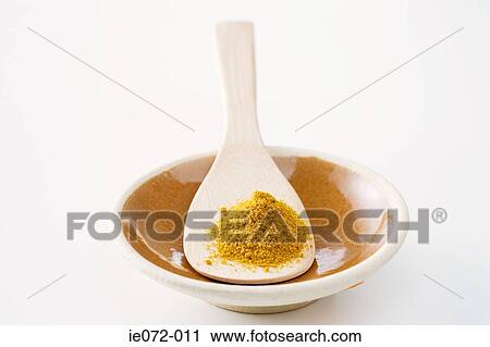 Stock Image - Curry powder wooden spoon and bowl. Fotosearch