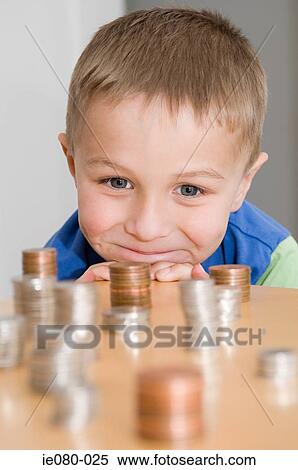 Boy looking at stacks of coins View Large Photo Image Stock Photography - Boy looking at stacks of coins. Fotosearch
