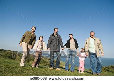 Stock Photo - Family holding hands on a grassy hill. Fotosearch
