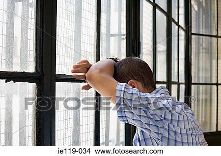 Picture - Teenage boy leaning against a window. Fotosearch