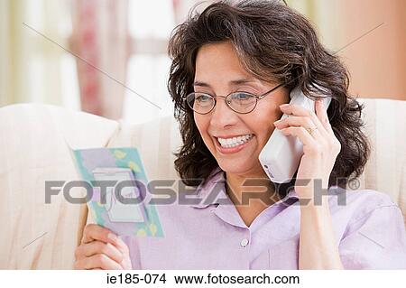 Picture - Woman on telephone with card. Fotosearch