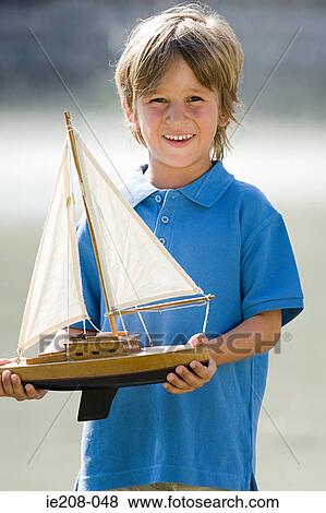 Boy with a toy boat View Large Photo Image Stock Photo - Boy with a toy boat. Fotosearch