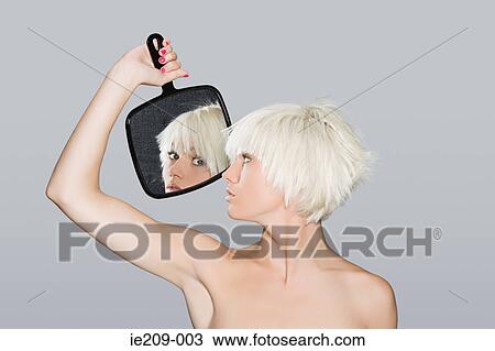 A woman looking at her reflection View Large Photo Image Stock Image - A woman looking at her reflection. Fotosearch