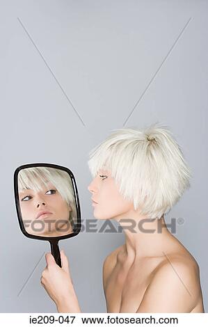 A woman looking at her reflection View Large Photo Image Stock Photo - A woman looking at her reflection. Fotosearch