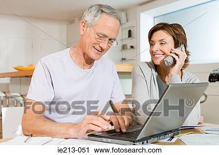 A couple using a phone and laptop View Large Photo Image Stock Image - A couple using a phone and laptop. Fotosearch