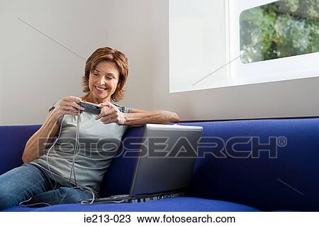 Stock Image - A woman using a laptop and digital camera. Fotosearch