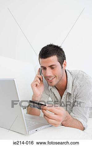 Stock Photograph - Man with credit card laptop and cellphone. Fotosearch