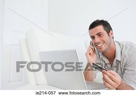 Stock Photo - Man with laptop cellphone and credit card. Fotosearch